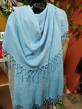 Load image into Gallery viewer, FALL/WINTER WRAP SWEATER/SHAWL WITH MATCHING MACRAME FRINGE. LIGHT BLUE SHAWL HANGING ON DISPLAY RACK. OTHER COLORS ARE SAGE, BROWN, BLACK, AND RUST.