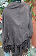 Load image into Gallery viewer, FALL/WINTER WRAP SWEATER/SHAWL WITH MATCHING MACRAME FRINGE. BROWN SHAWL HANGING ON DISPLAY RACK. OTHER COLORS ARE SAGE, BLACK, LIGHT BLUE, AND RUST.