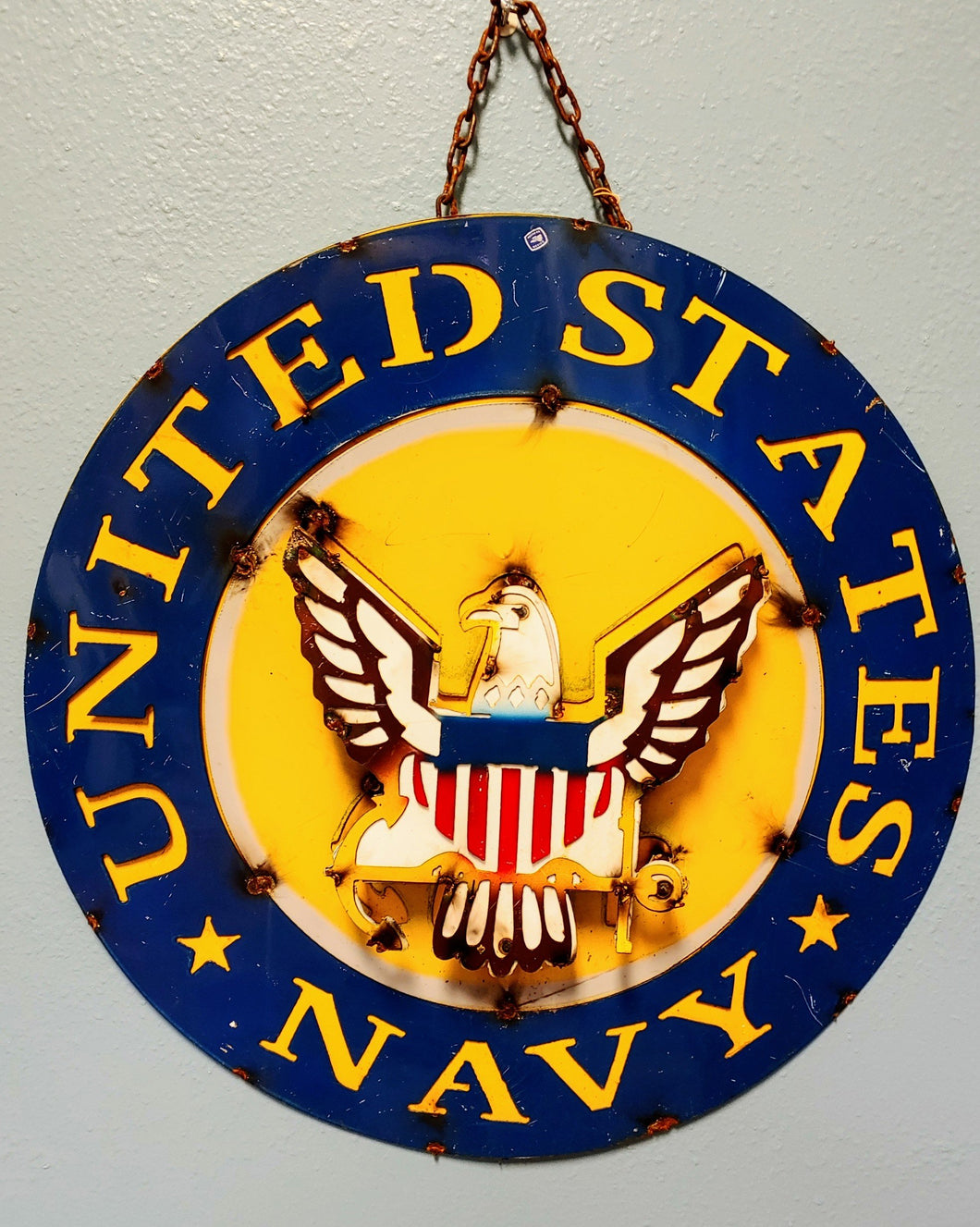 United States Navy round metal sign, yellow lettering with navy blue background. Bald eagle featured in the center that is 3D. 2 inches raised from the sign.
