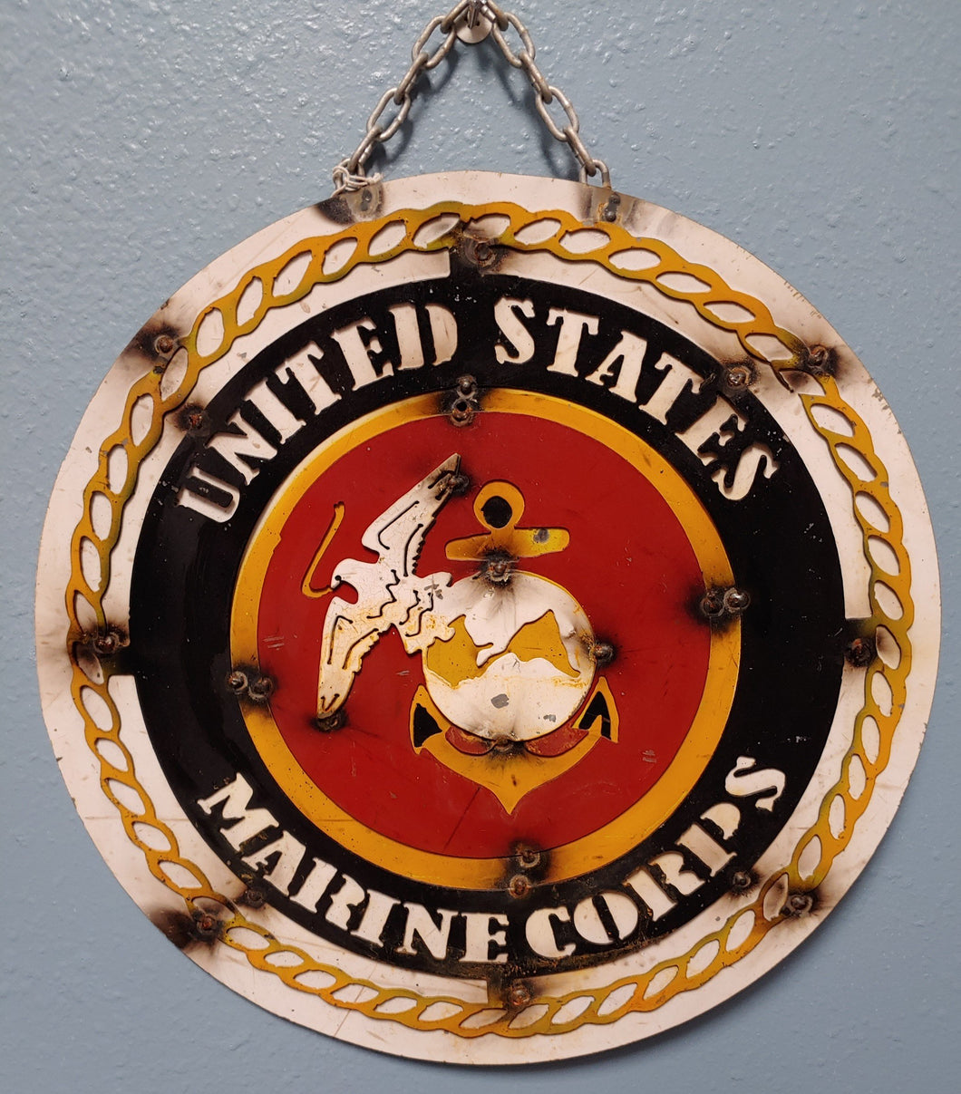 Heavy gauge round metal sign hanging on a sturdy metal chain.  United States Marine emblem with red background, navy and with white lettering and gold chain decor with white background. weathered and rusted finish.  Very handsome sign.