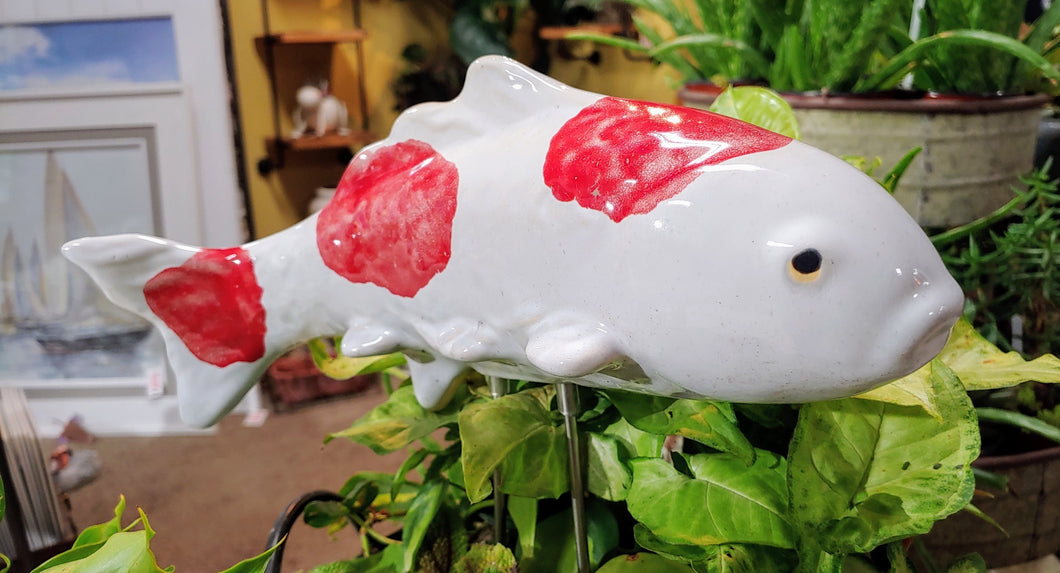 white ceramic koi fish on metal stake with red dots