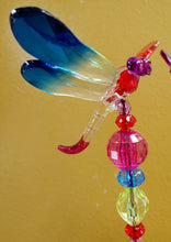 Load image into Gallery viewer, IMAGE OF 1 DRAGONFLY AND STAKE AGAINST A YELLOW WALL. THE BODY IS CLEAR. THE HEAD IS PURPLE;  LEFT WINGS ARE RED; RIGHT WINGS ARE DARK BLUE, AND THE TIP OF TAIL IS DARK PURPLE. THE STAKE SHOWS SMALL DARK PURPLE, SMALL RED, LARGE PURPLE, SMALL BLUE, LARGE YELLOW, SMALL RED, AND SMALL PURPLE BEADS.  RedShedGarden redshedgarden RedShedredshed Baraboo Gifts Mother’s Day Birthday Anniversary Garden Stakes Dragonflies Just Because