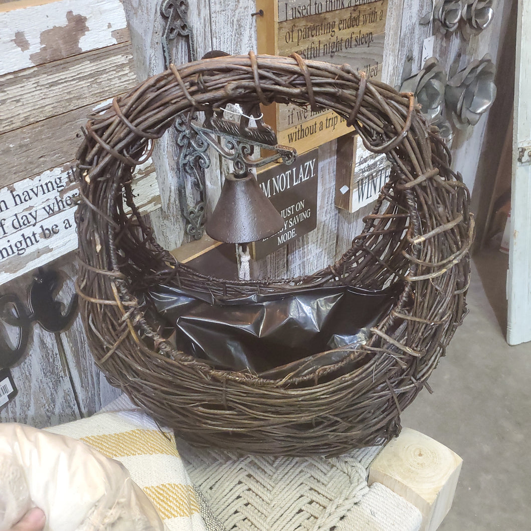 brown wicker basket with large handle.  Has a plastic insert for a house plant or fresh flowers