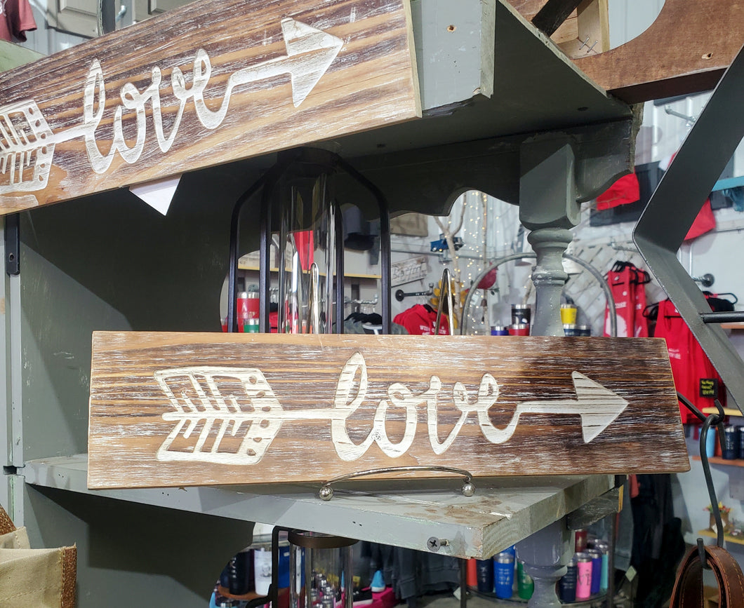2 TAN, WOODEN PLANKS WITH A WHITE ARROW | MIDDLE OF ARROW SAYS ‘LOVE.’