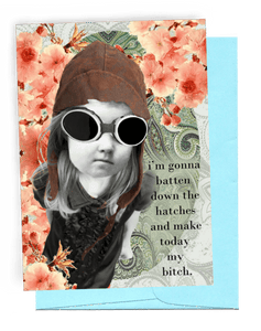 GREETING CARD | LIGHT BLUE ENVELOPE. | BACKGROUND: DOLLAR-COLORED, FLEUR-DE-LIS/BRIGHT PINK FLOWERS | GIRL WEARING OLD-FASHIONED, FOOTBALL HELMET-LIKE CAP/LARGE SAFETY GLASSES FOR FLYING | LONG, BLOND HAIR/PUFFED, SHORT-SLEEVED BLOUSE WITH RUFFLED FRONT | LOOKING STUBBORN WITH FIST | WORDS: OUTSIDE, "I'M GONNA BATTEN DOWN THE HATCHES AND MAKE TODAY MY BITCH." INSIDE, "...EVERYBODY STAND BACK!!!"