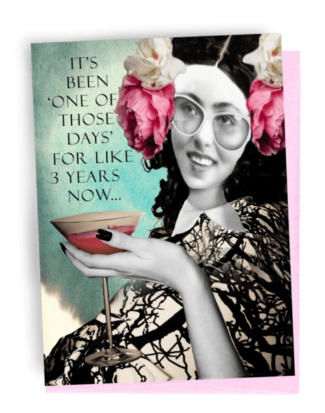 A GREETING CARD, PINK ENVELOPE. WOMAN WITH DARK SHOULDER-LENGTH HAIR, PINK FLOWER, AND WHITE FLOWER ON BOTH SIDES OF HEAD, WEARING, WHITE-FRAMED GLASSES. WEARING TREE-STAMPED WHITE DRESS. BLACK NAIL POLISHED HAND COMES FROM BOTTOM HOLDING A MARTINI. TOP LEFT HAS BLUE BACKGROUND; WORDS OUTSIDE -- IT’S ‘ONE OF THOSE DAYS’ FOR LIKE 3 YEARS NOW…INSIDE I’M BEGINNING TO THINK IT MAY JUST BE ME! 