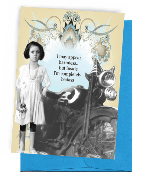 A GREETING CARD WITH A BLUE ENVELOPE. A PALE YELLOW BACKGROUND WITH ARTISTIC FLOWERS AT THE TOP AND A MOTORCYCLE AT THE BOTTOM. A YOUNG GIRL IS LEANING ON THE MOTORCYCLE HOLDING A SMALL DOLL. WORDS OUTSIDE – ‘I MAY APPEAL HARMLESS...BUT INSIDE I’M COMPLETELY BADASS.’ INSIDE: BLANK.