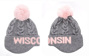 Women's winter hat.  Gray cable knit with ear warmers.  "Wisconsin" is knitted in the forehead portion of the hat.  There is a pink pom pom on the top of the hat
