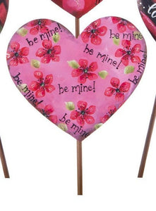 pink metal heart on a stake.  be mine!  and pink flowers with green leaves on painted on it.  Touch of glitter to add sparkle