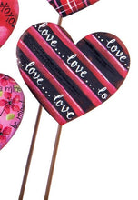 Load image into Gallery viewer, metal heart shaped plant stake for valentine&#39;s day.  This is red and black striped with love...love....love written in every other black stripe.  There is a hint of glitter for sparkle