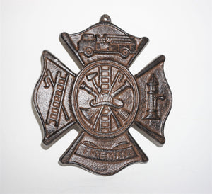 Cast iron shield with 4 flags, one with a fire truck, one with fire hydrant, one says Fireman, and finally a hook and ladder.