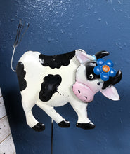 Load image into Gallery viewer, METAL COW 6 INCHES TALL BY 8 INCHES WIDE ON A METAL STAKE. COLORS ARE BLACK AND WHITE COW WITH BLACK HORNS AND A BLUE FLOWER ON ITS HEAD, AGAINST A BLUE WALL.