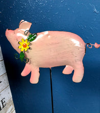 Load image into Gallery viewer, METAL PIG 6 INCHES TALL BY 8 INCHES WIDE ON A METAL STAKE. COLORS IS ALL PINK WITH A CURLY TAIL WEARING A YELLOW FLOWER WITH GREEN VINES AROUND ITS NECK, AGAINST A BLUE WALL.