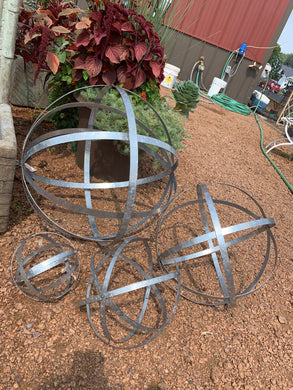 4 SILVER-COLORED METAL FOLDING SPHERES | 8”, 12”, 18”, 23” | STRAIGHT-ON VIEW OF ALL 4 OPENED | EACH HAS 5 IRON BANDS ROUGHLY 5/8 INCH THICK | WILL COLLAPSE OR EXPAND AS YOU NEED.