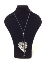 Load image into Gallery viewer, Heart Lock and Key Pendant Necklace. 2.5&quot; W x 2.75&quot; high Heart Lock and 2&quot;Lx.5W Key hang on a 16&quot; smooth black braided cord. The cord has a single accent bead above the pendant and there is a 1.75 extender chain but will easily slip over the head. 