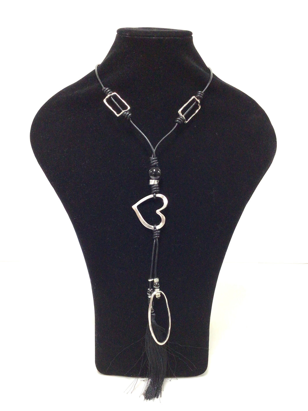 A modern, stylish necklace.  Pendant features an open heart, an elongated oval and a black silklike tassel. There are two 1.25