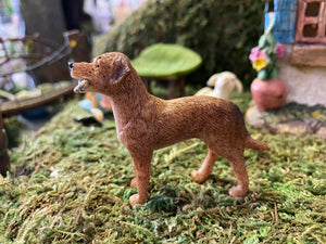 FAIRY GARDEN – RESIN – ‘FETCH’ FAIRY DOG | MG49 | 4.41” T BY 4.25” W BY 4.17” D | ALWAYS READY TO PLAY IN YOUR MINIATURE OR FAIRY GARDEN | LIGHT TAN COAT WITH WHITE CHEST | FINELY DETAILED FUR | WHITE STICK IN ITS MOUTH | SIDE VIEW.