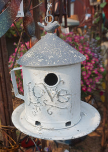 White metal birdhouse with "LOVE" embossed on the front. Silver galvanized metal roof with a small bird sitting on top. There is a metal chain for the feeder to hang. The base screws off to fill with bird food or to clean out if used as a birdhouse. Antique rustic paint job to make it look Vintage.