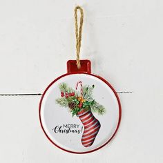 This is a round tin ornament that states Marry Christmas. It has a red striped stocking that is filled with pine boughs. It's has a simple classic look that will make it a favorite for  years to come. As it is made of tin it can be hung indoors or outdoors.