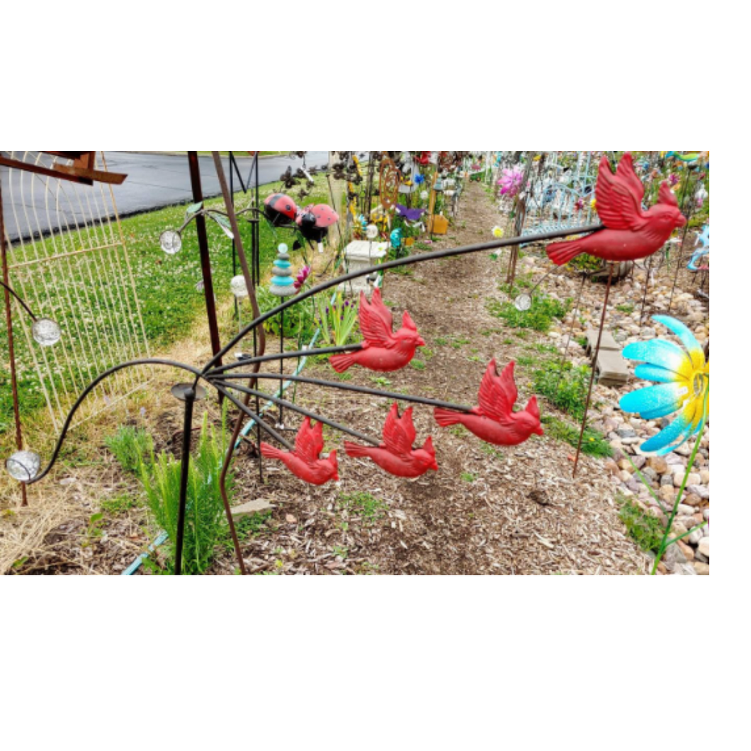 5 Red cardinals each on their own stake balancing on a garden stake.  There is a giant glass ball on the other end of the balancing birds that keeps them on the garden stake.