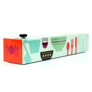 ‘CHICWRAP’ PROFESSIONAL PLASTIC WRAP DISPENSER | 12” BY 250” ROLL, BPA-FREE, PROFESSIONAL-GRADE PLASTIC WRAP IN COLORFUL DISPENSERS | 4 RUBBER FEET | PATENTED ‘ZIPSAFE’ SLIDE CUTTER | KOSHER AND HALAL CERTIFIED | MICROWAVE SAFE | REFILL WITH ANY STORE-BOUGHT PLASTIC WRAP | DISPENSER WITH KITCHEN TOOLS ON LIGHT GREEN BACKGROUND ON SIDES | TABLE SETTING ON ORANGE BACKGROUND ON ENDS.