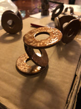 Load image into Gallery viewer, 4 METAL AIR PLANT STANDS. 3 LARGE WASHERS WELDED TOGETHER TO FORM A ‘Z.’ SITTING ON A BOX. BEHIND ARE 3 MORE ‘WELDED WASHERS’ PLANT STANDS FORMED INTO CIRCLES. ALL ARE PAINTED METALLIC COPPER. 