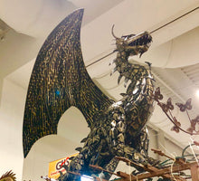 Load image into Gallery viewer, A BLACK POWDER-COATED DRAGON. SITS ON TOP OF A BROWN METAL PLANT SCAFFOLDING. SHOWS PART OF BROWN BUTTERFLIES ON BROWN METAL VINES.