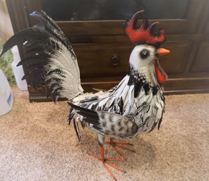 THIS BLACK AND WHITE METAL ROOSTER IS SITTING ON A CEMENT FLOOR, FACING RIGHT. IT HAS POWDER-COATED IRON|IS 23 INCHES LONG BY 9 INCHES WIDE BY 23 INCHES HIGH. IT IS FREESTANDING WITH MALLEABLE FEATHERS AND HAS A HAND-PAINTED NATURAL FINISH.