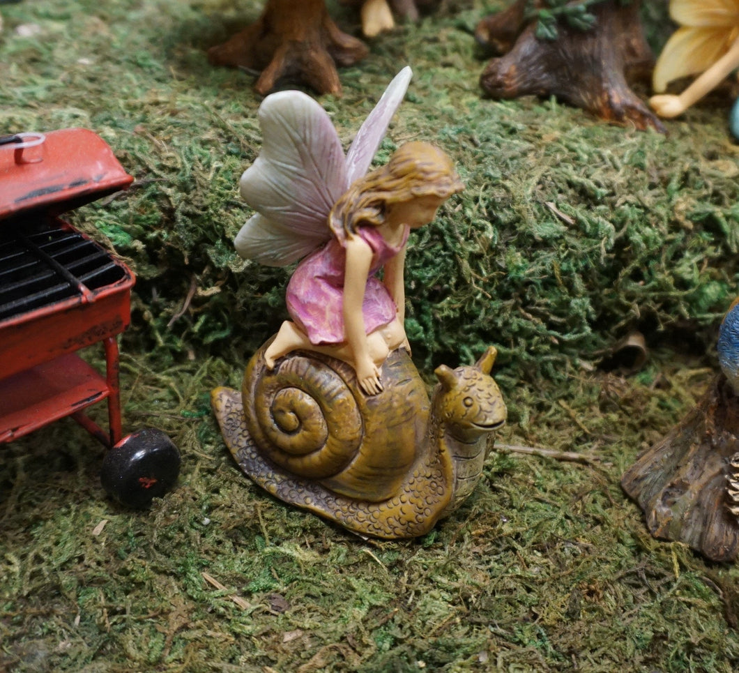 FAIRY IN A PINK DRESS KNEELING ON A BROWN SNAIL|3 INCHES TALL. THEY ARE IN THE FAIRY GARDEN.
