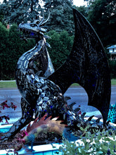 Load image into Gallery viewer, A BLACK POWDER-COATED DRAGON SITTING ON DIRT OUTSIDE IN SUNLIGHT. HAS A GREEN BRANCH IN THE FOREGROUND. SHOWS A DRIVEWAY, LAWN, TREES, AND A HOUSE IN THE BACKGROUND.