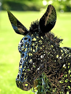 IMAGE OF AN ANTIQUE BRONZE-FINISHED, FILIGREE METAL DONKEY’S HEAD FROM THE FRONT. SHOWS THE FINE DETAILS OF THE HEAD, NECK, AND EARS. IT HAS A BLURRY BACKGROUND OF A LAWN. RedShedGarden redshedgarden RedShedredshed Baraboo Gifts Birthday Mother’s Day Anniversary Garden Decor Donkey Metal Sculpture Just Because