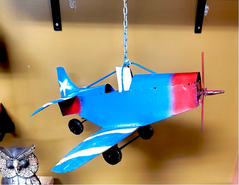 hanging metal airplane statue.  It is painted blue with the front propellers and nose painted red.  3 wheels that are painted black.  There are white stripes on  the wings and back wings.  The tail has a white star painted on it.  Hanger has a hook.