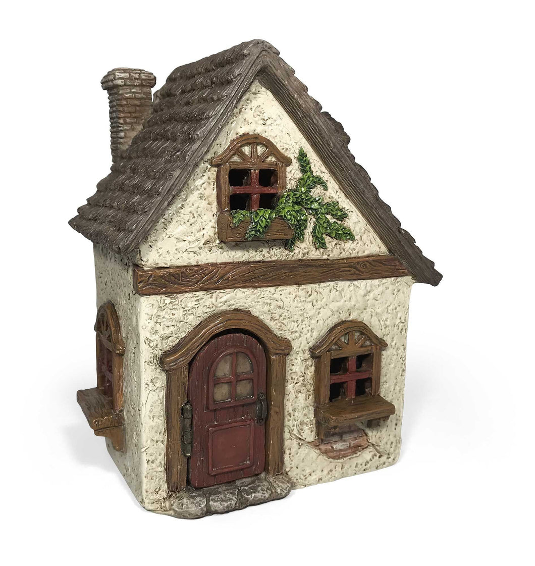 Cute miniature white stucco house with a cedar shake shingle roof.  Wooden accents around the door and windows.  Window box with vines on the second floor of the fairy cottage.  Brick chimney and cobblestone enterance.  
