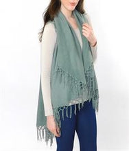 Load image into Gallery viewer, FALL/WINTER WRAP SWEATER/SHAWL WITH MATCHING MACRAME FRINGE. WOMAN WEARING A SAGE SHAWL OVER WHITE, LONG-SLEEVED SWEATER, AND BLUE JEANS. OTHER COLORS ARE BLACK. BROWN, LIGHT BLUE, AND RUST.