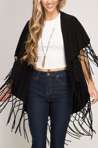 FALL/WINTER WRAP SWEATER/SHAWL WITH MATCHING MACRAME FRINGE. WOMAN WEARING A BLACK SHAWL OVER WHITE, SLEEVELESS SWEATER, TURQUOISE/GOLD NECKLACE, AND BLUE JEANS. OTHER COLORS ARE SAGE, BROWN, LIGHT BLUE, AND RUST.